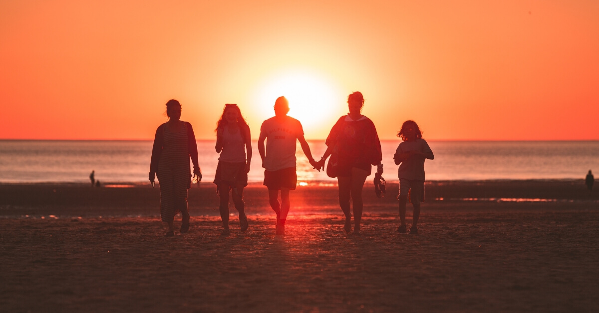 family walking at the beach at sunset