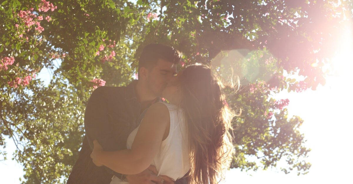 man kissing woman under a tree