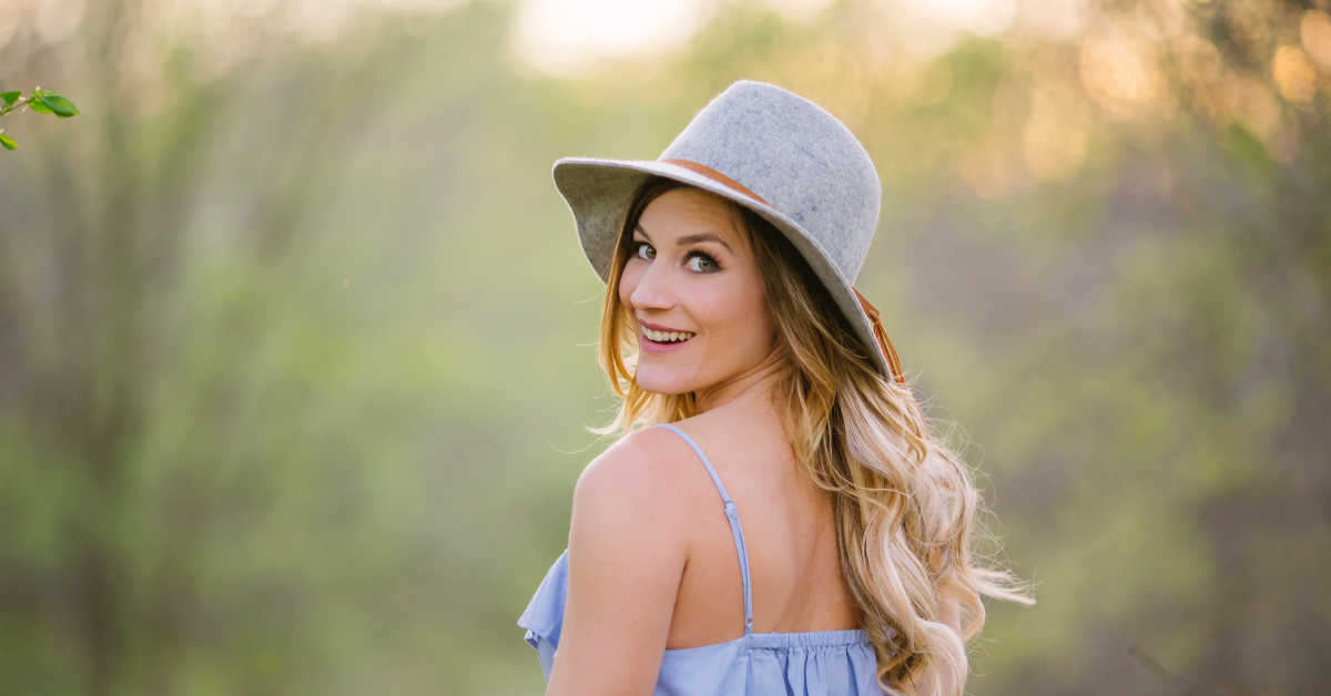 Woman in grey felt hat looking over her shoulder smiling