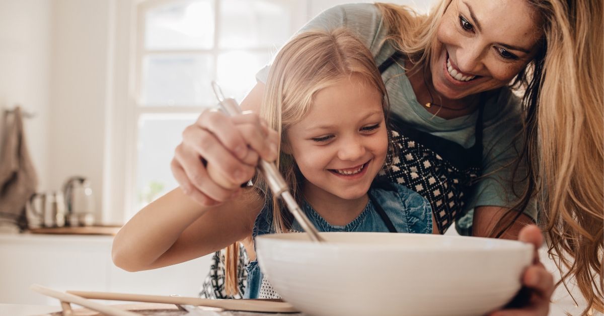 photo of a happy mum and daughter stirring a baking bowl