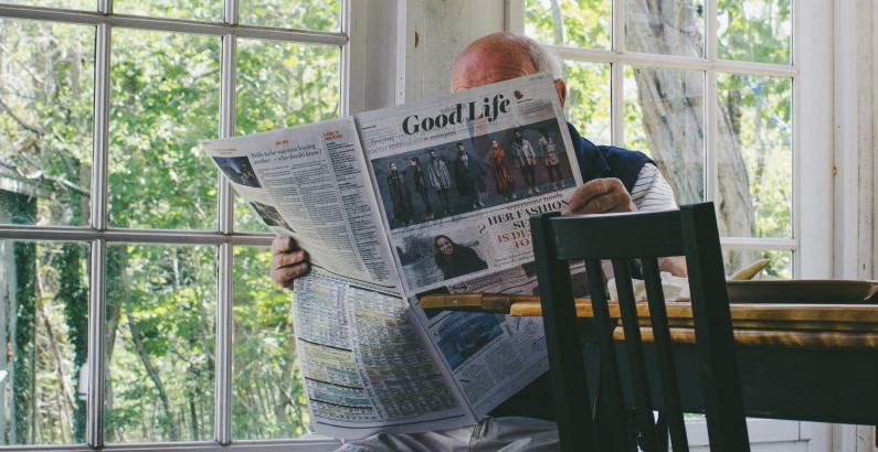 photo of a senior man at home reading newspaper
