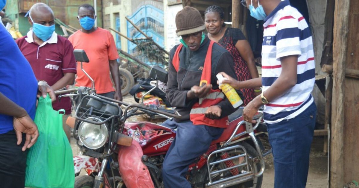 kenyans wearing masks and receiving hand sanitiser from african enterprise