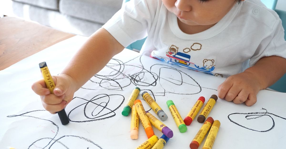 photo of kid scribbling with crayon on paper