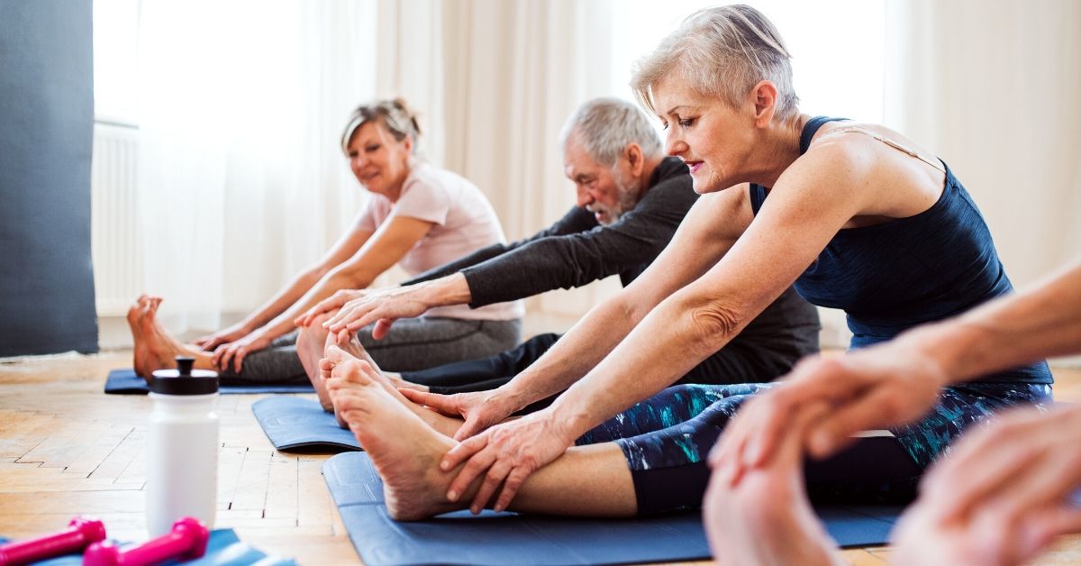 photo of elderly people sitting on yoga mats stretching