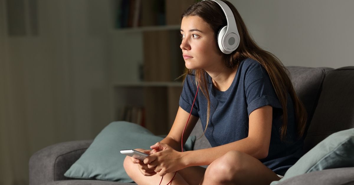 photo of girl with headphones on sitting on the couch in her home