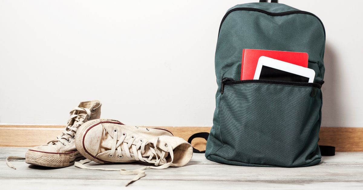 photo of a school bag and converse branded shoes against a white wall