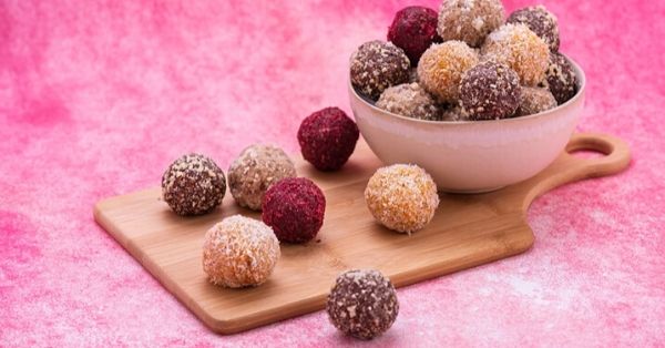 photo shows bliss balls in a bowl on a pink backdrop