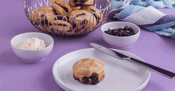 photo shows a blueberry scone on a plate next to some cream