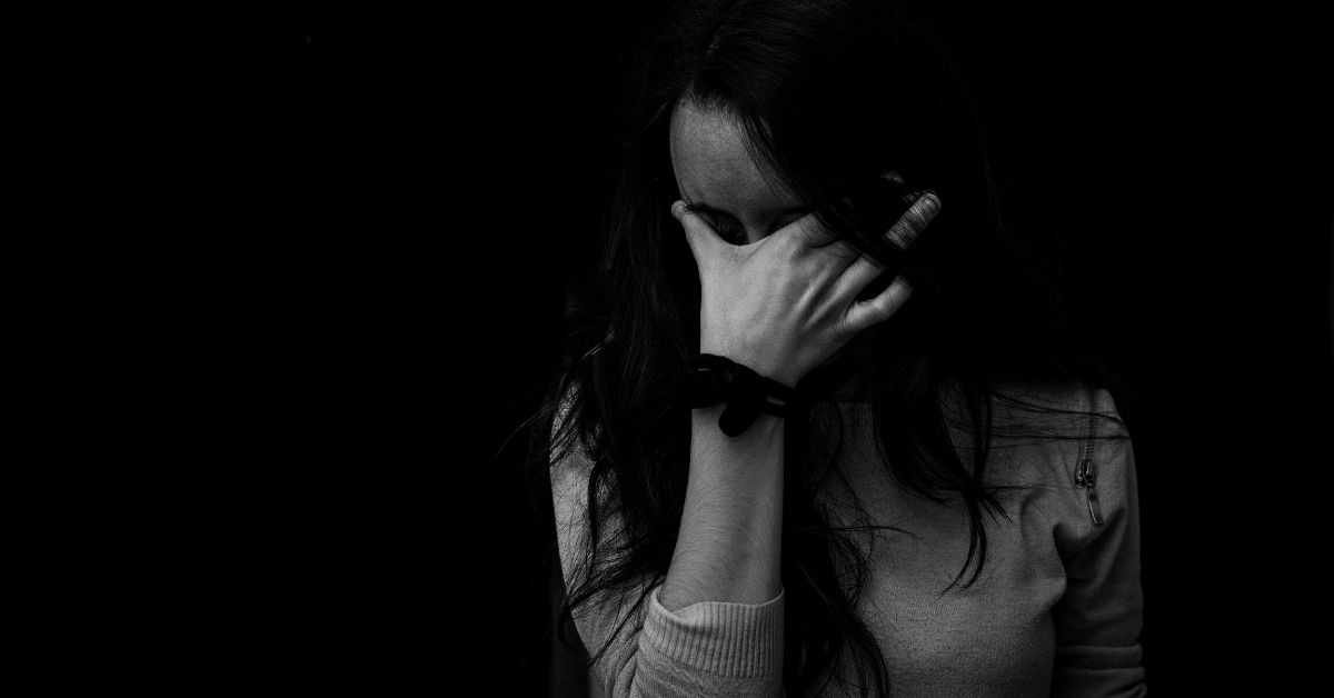 black and white photo of a distraught woman with her face in her hand