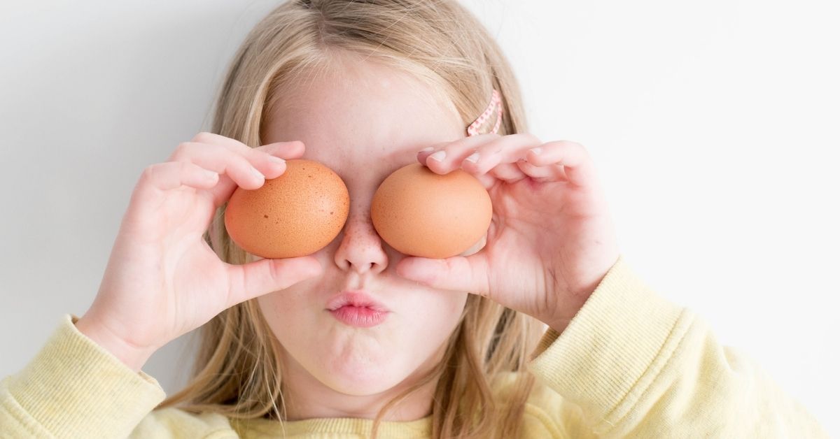girl holding eggs over her eyes