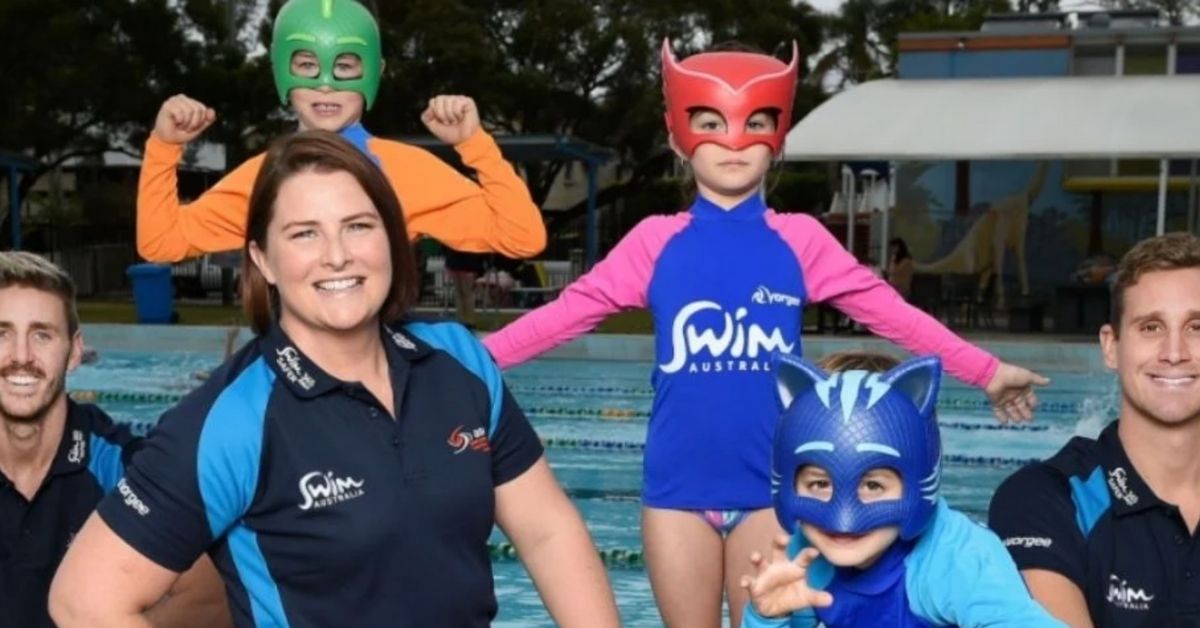 swim australia team posing with kids in the water