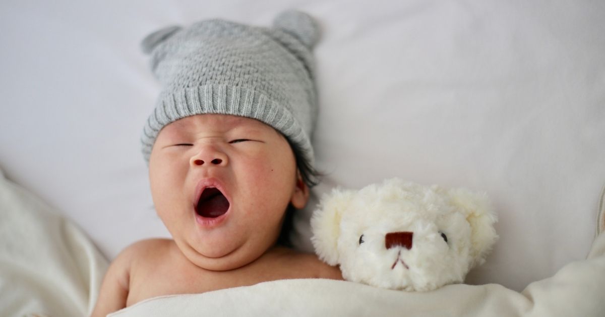 Baby yawning and teddy bear