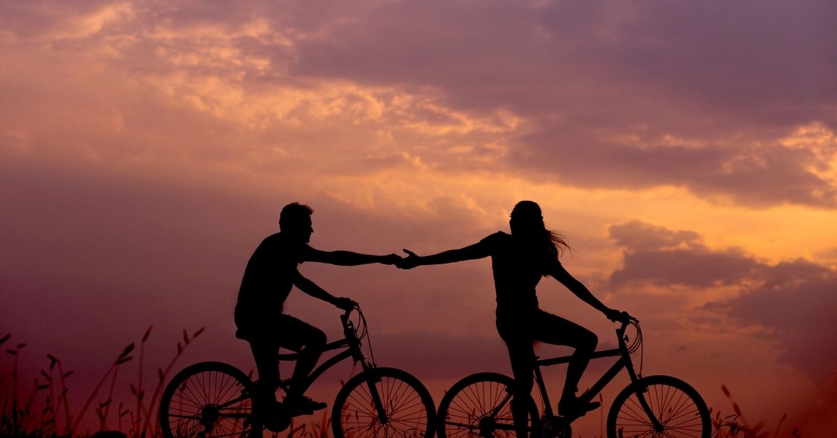 Couple riding bikes at sunset