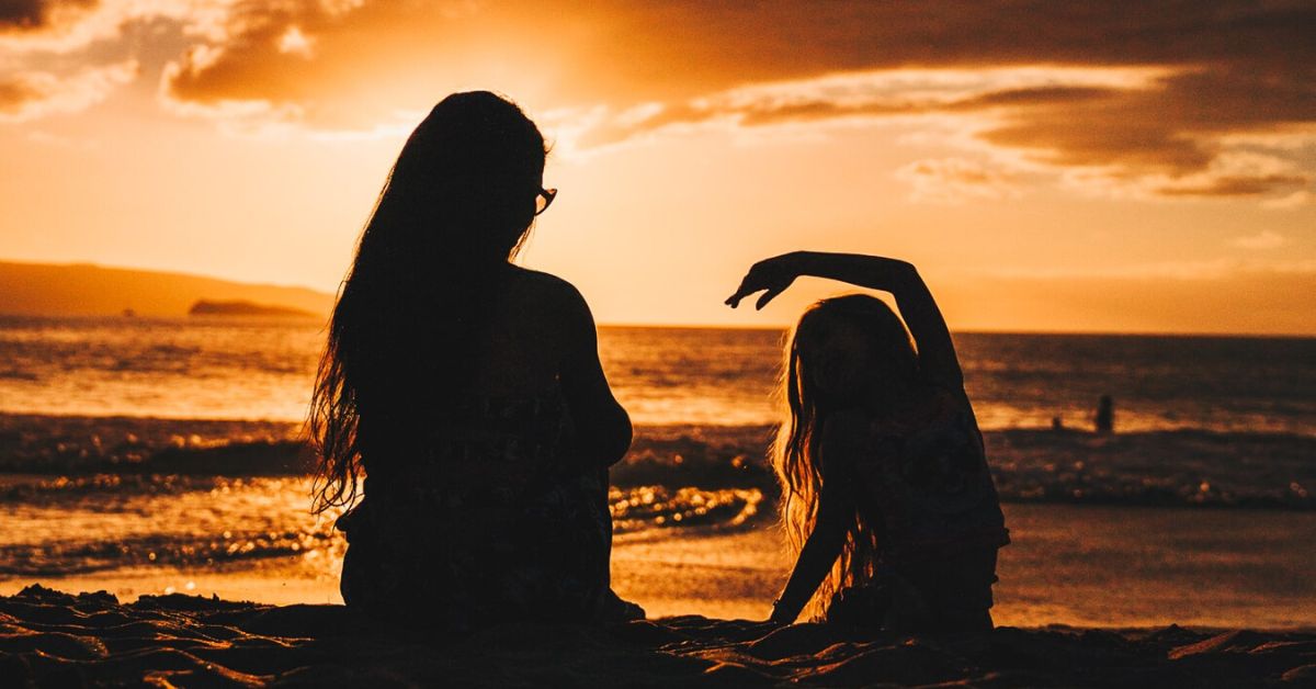 Woman and daughter on beach at sunset