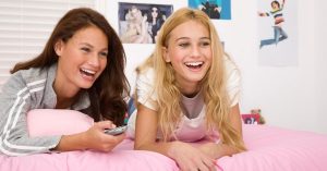 two girls lying on a pink bed laughing