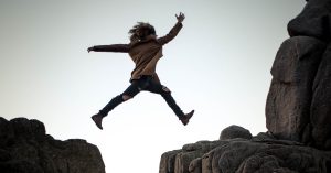 person leaping from one rock to another