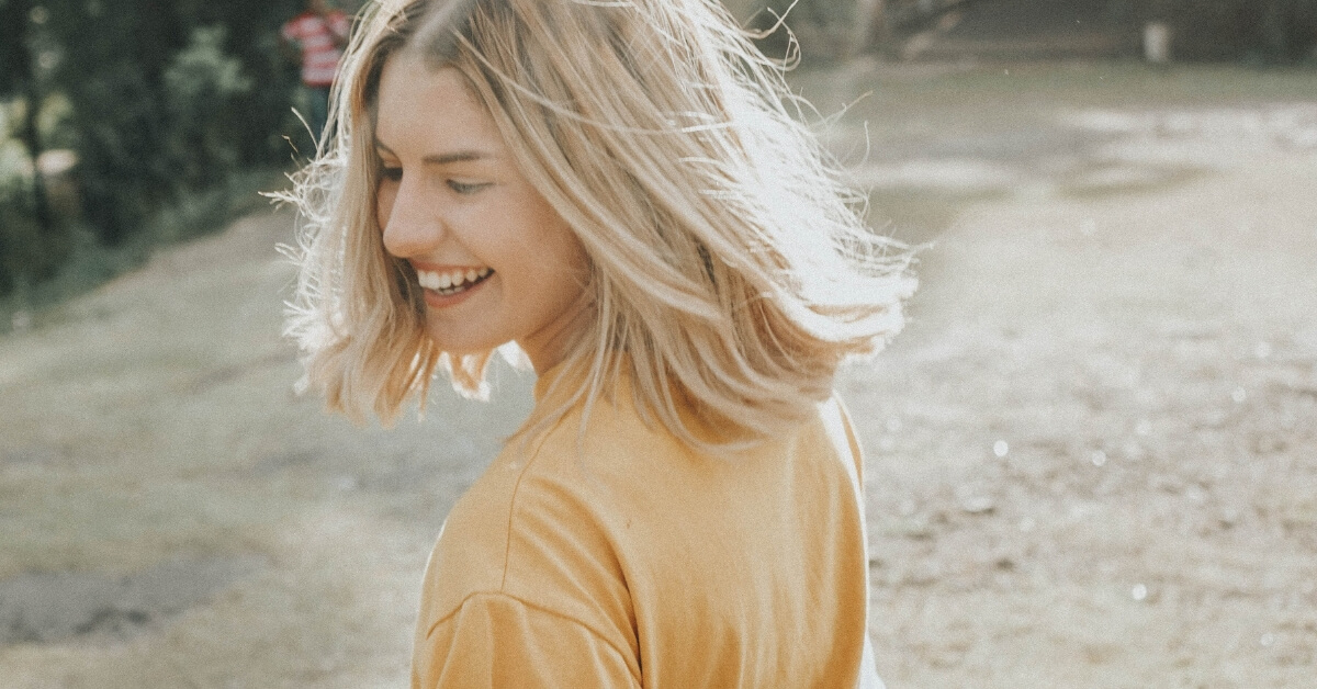 woman in yellow top laughing in the sunshine