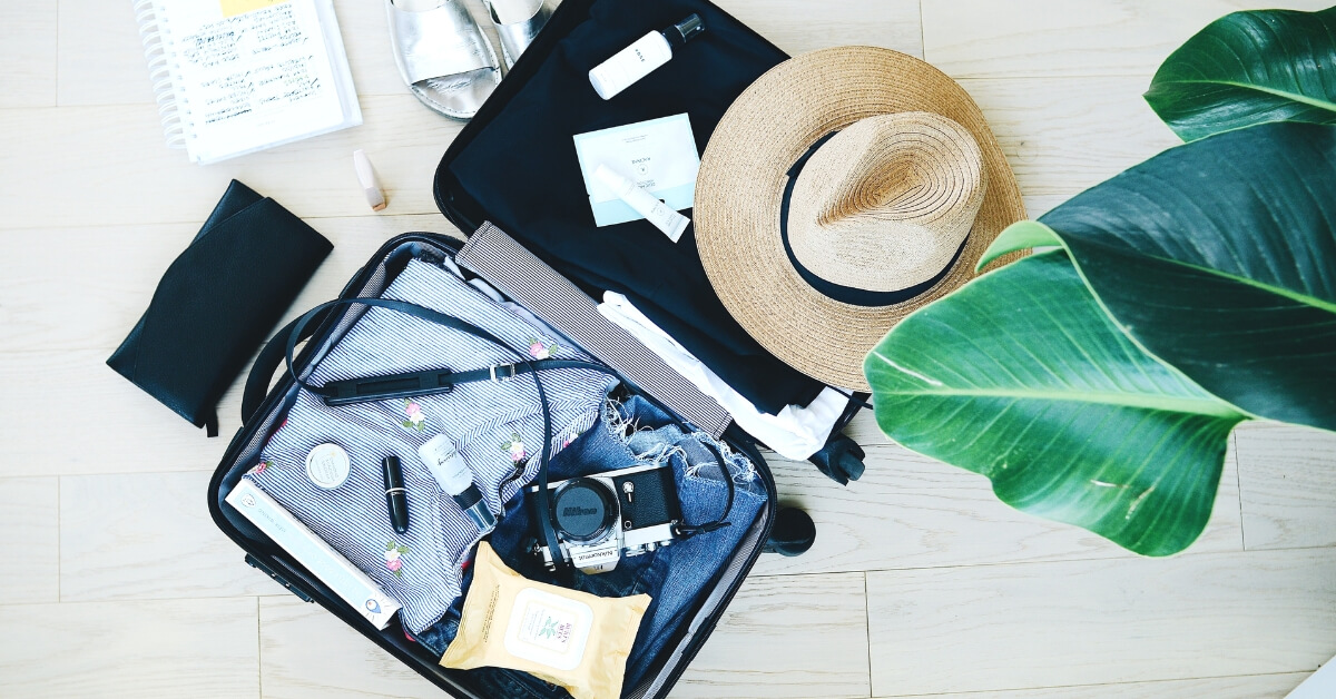 flatlay of open suitcase containing travel items beautifully laid out