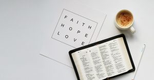 a bible, cup of coffee and a quote card which reads" faith, hope, love"