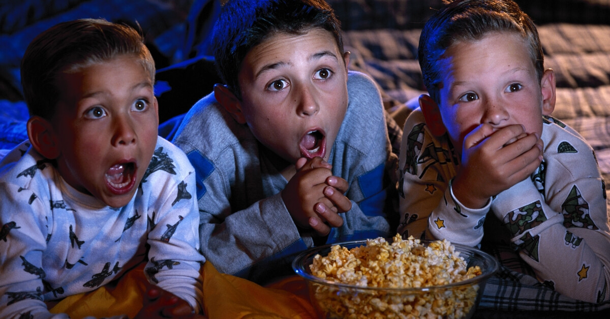 scared kids watching a movie with bowl of popcorn