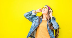 happy woman wearing sunglasses in front of a yellow wall