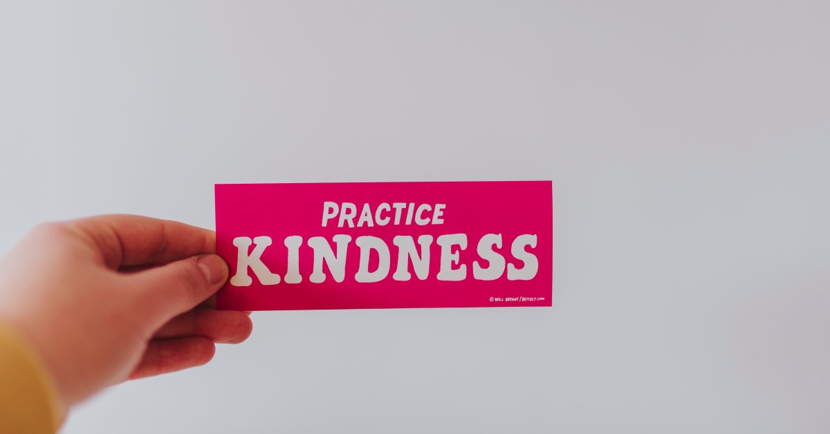 Hand holding a card that says Practice Kindness