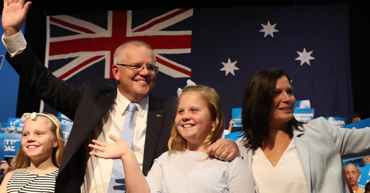 Scott Morrison and his family waving to supporters in front of an Australian flag