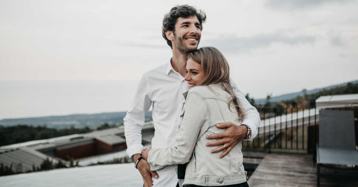 Couple in white hugging on building roof