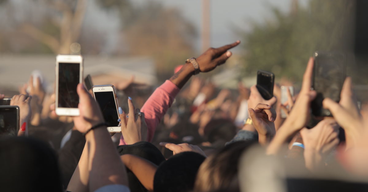hands lifted in a crowd with smartphones