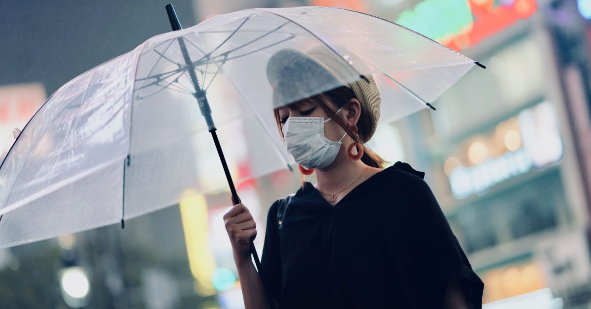 Women wearing mask holding an umbrella