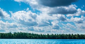 looking from the ocean up to blue sky full of clouds