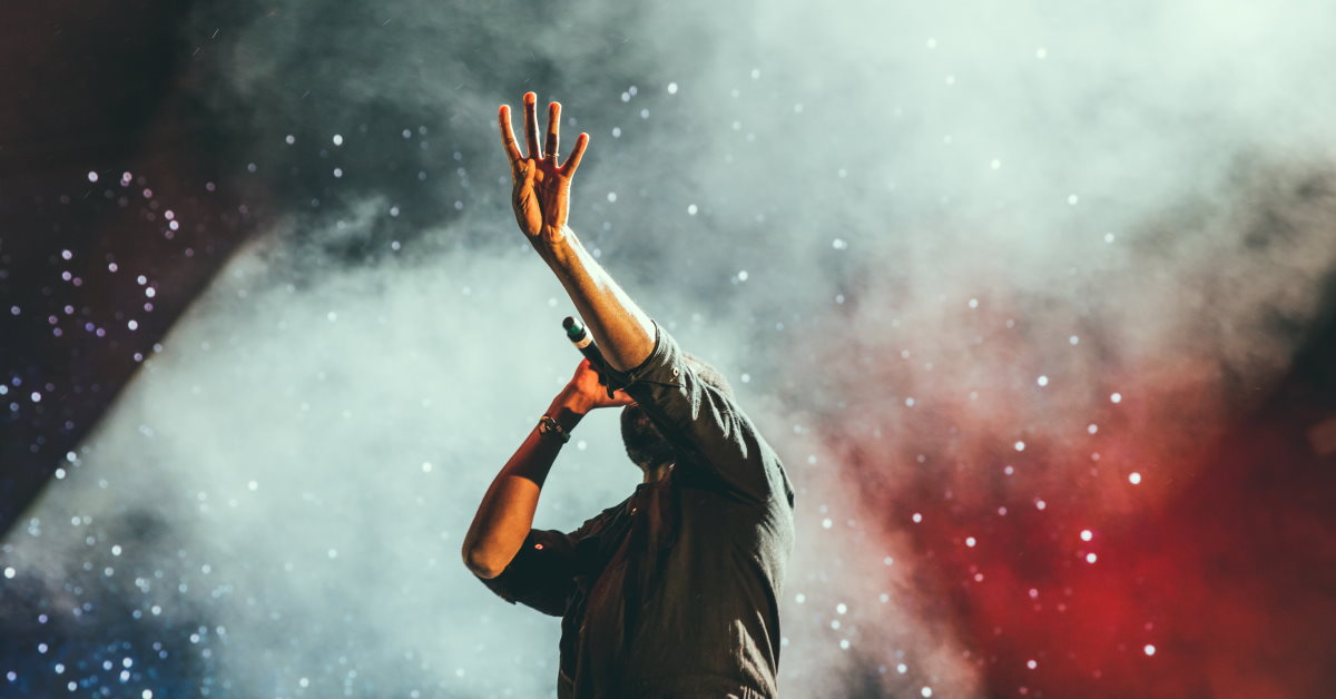 guy singing from stage reaching out in worship