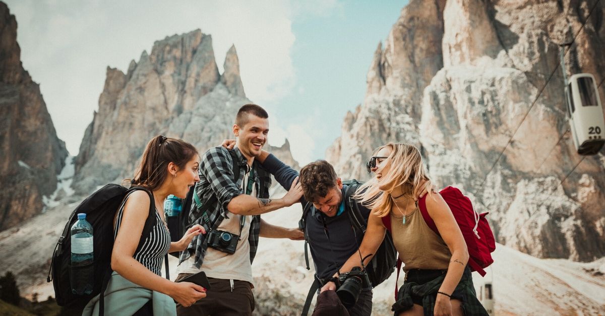 photo of a group of friends hikinh with mountains in the background, laughing