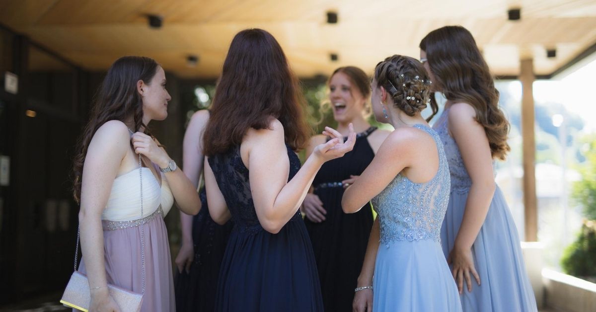 a group of girls talking and laughing wearing formal dresses