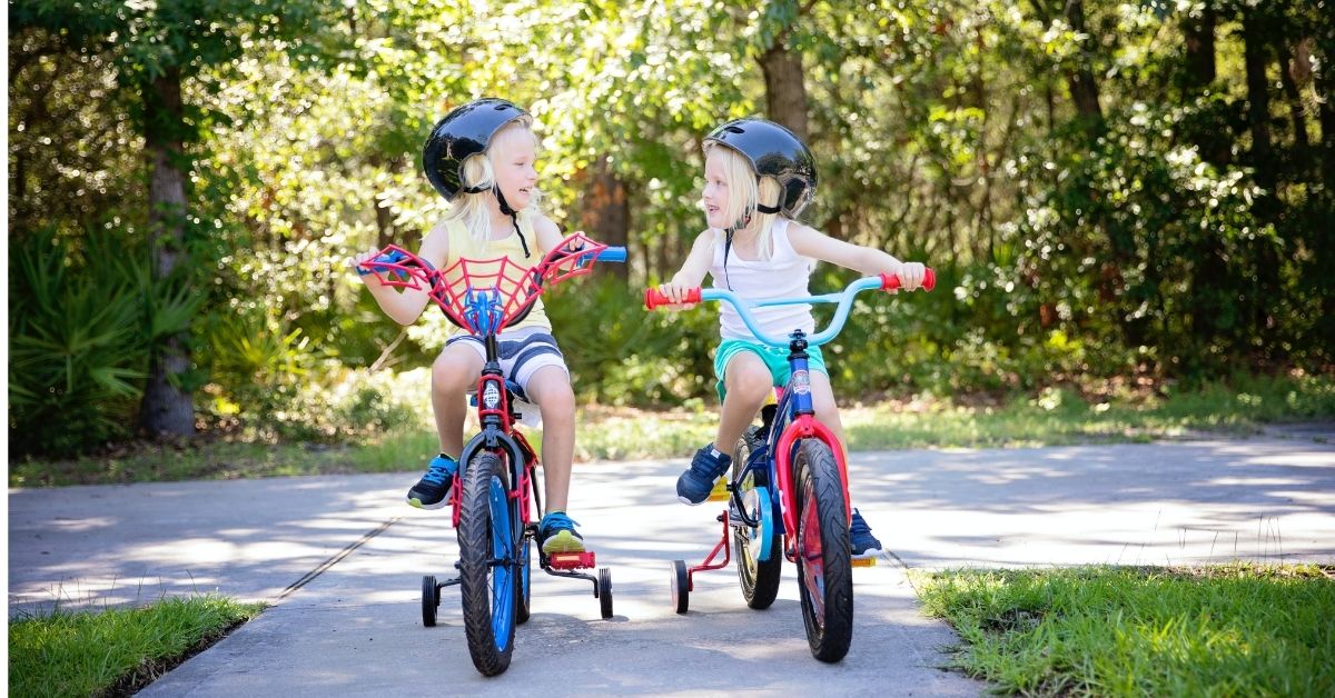 two young girls riding bikes with training wheels