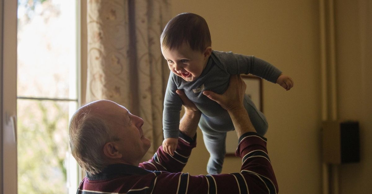 grandfather holding smiling baby in the air