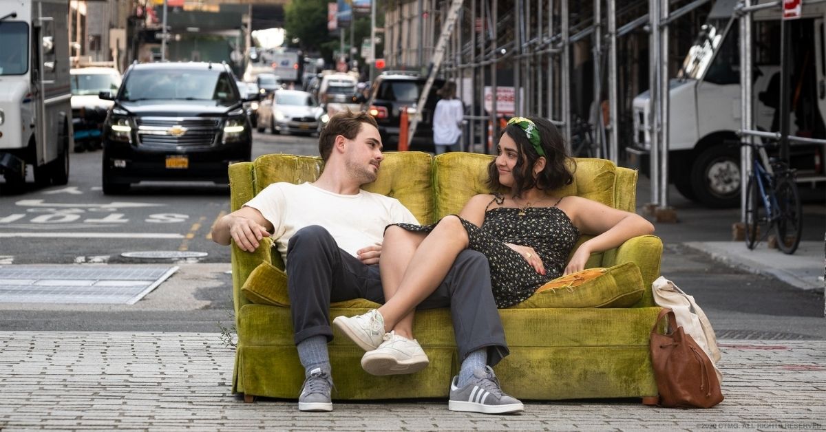 Lucy and Nick sitting on a yellow couch in the middle of the street gazing at each other