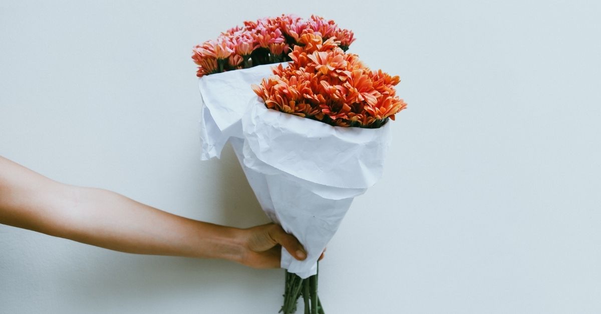 arm holding out two bouquets of flowers