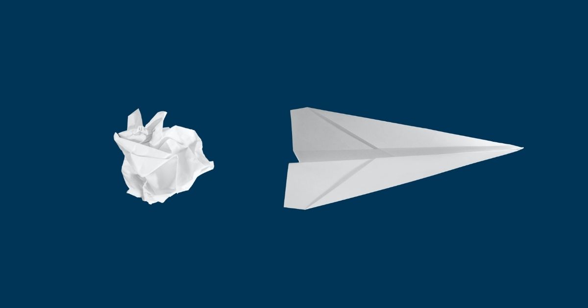 a paper plane beside a crumpled ball of paper
