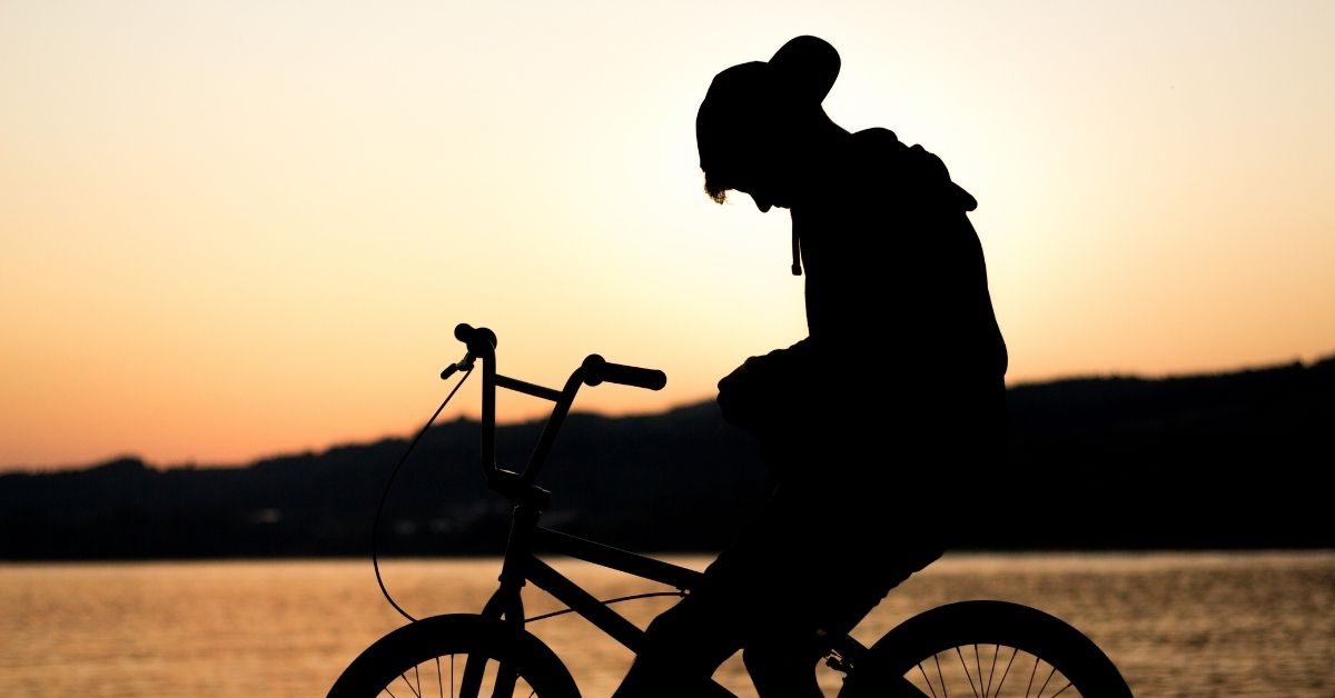 silhouette of a boy slumped on his bike