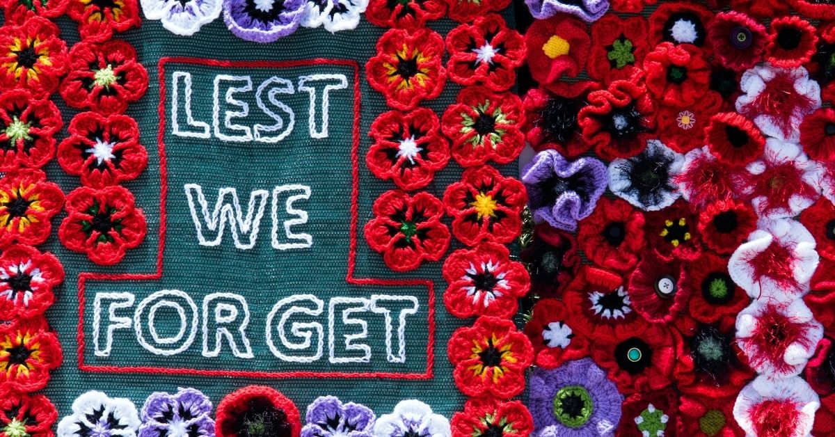 a knitted banner of poppies and wording "lest we forget"