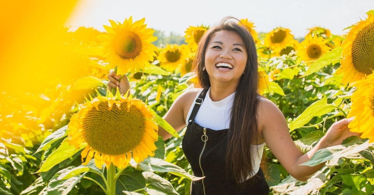 girl smiles standing in a sunflower field