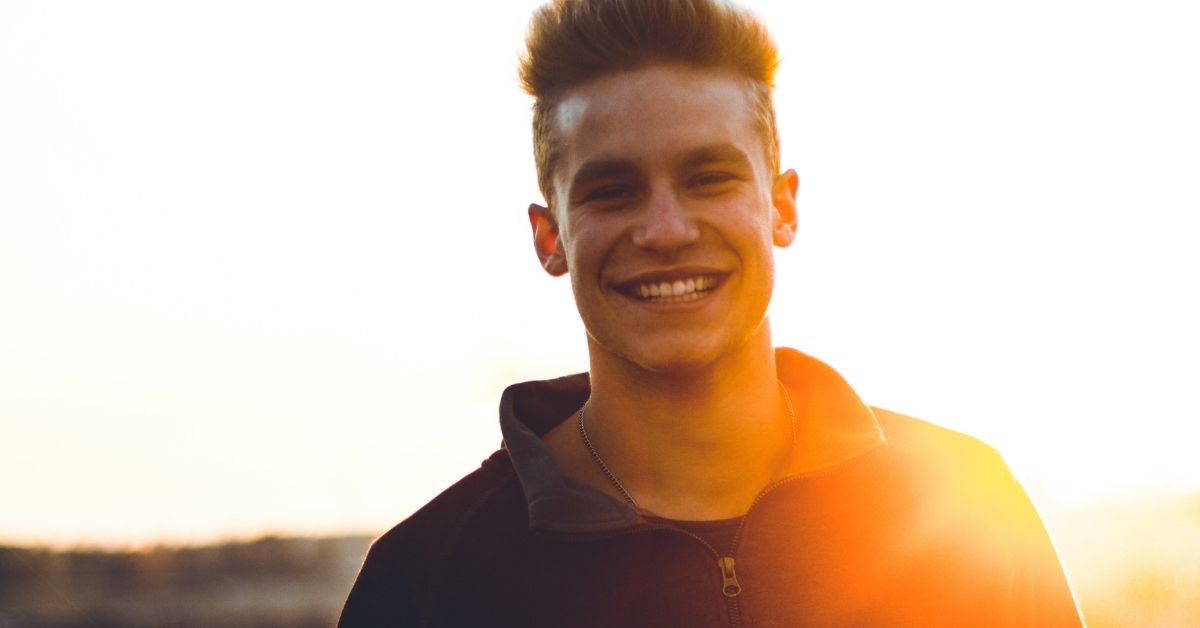 a man smiling backlit by a setting sun