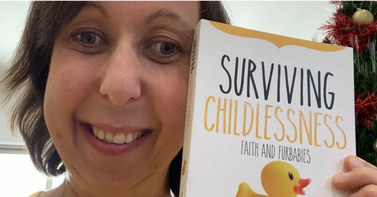 steph penny holding up her book surviving childlessness, faith and furbabies