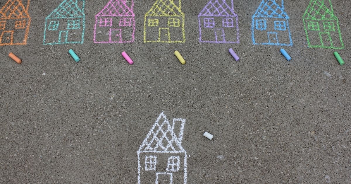 different coloured chalk drawings of houses on concrete pavement