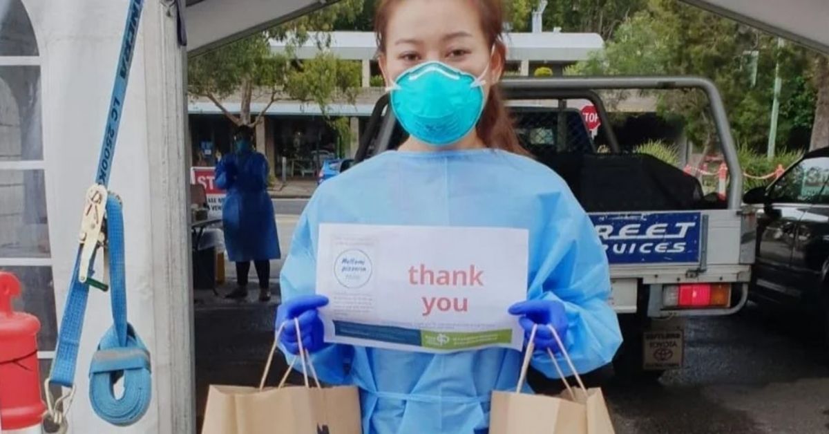 feed our medics hero image - a medical worker wearing a mask holds a sign saying thank you