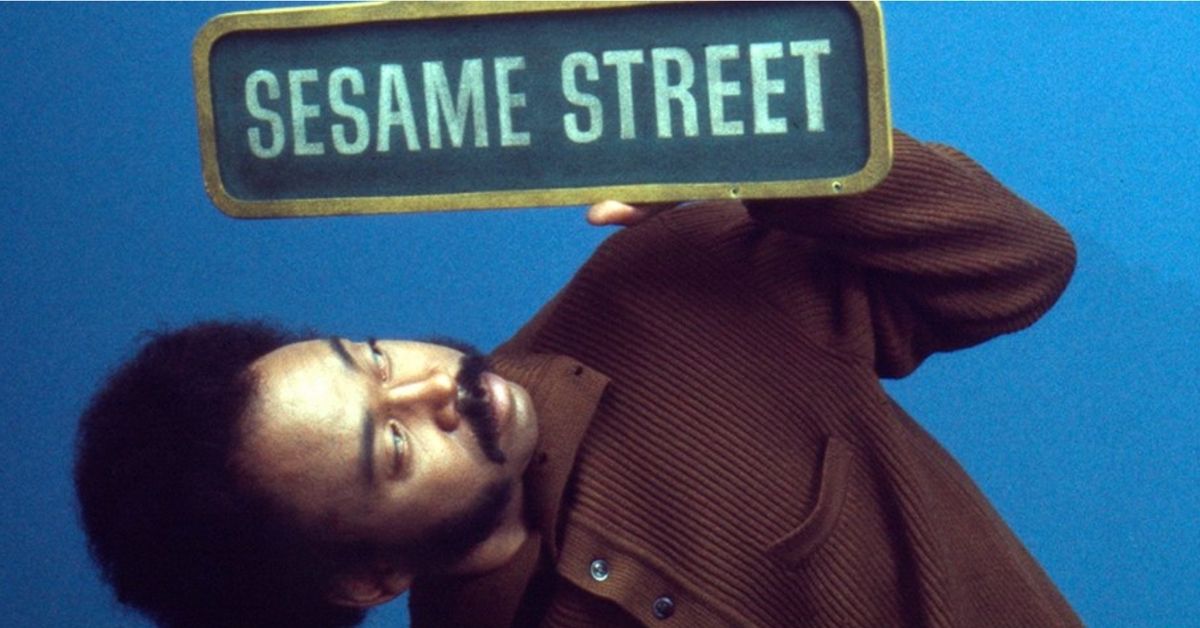 man holding sesame street sign