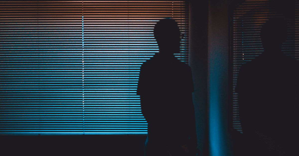 Man in a dark room looking at mirror
