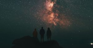 Three people looking up at night sky