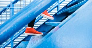 Person in red shoes walking up blue stairs